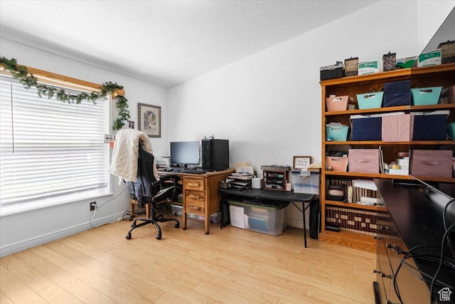 home office with plenty of natural light, wood finished floors, a textured ceiling, and baseboards