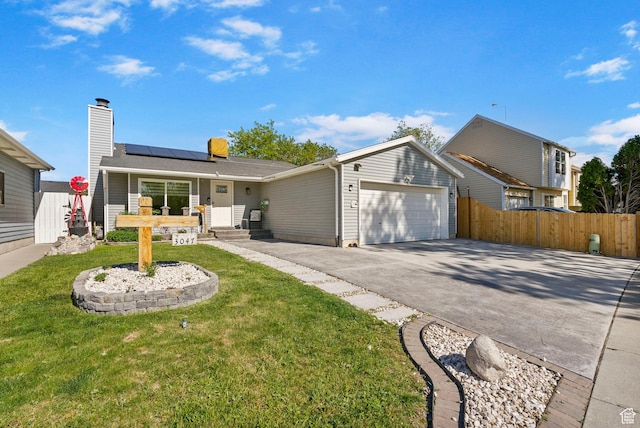 view of front of property featuring roof mounted solar panels, driveway, a garage, and a chimney