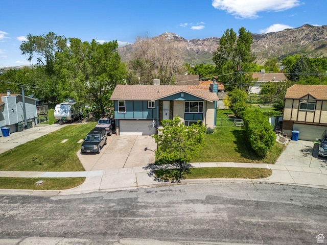 view of front facade featuring driveway, a mountain view, a garage, and a front lawn