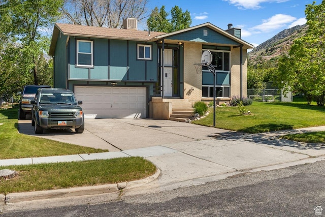 view of front of property featuring a chimney, driveway, a garage, a front yard, and a mountain view