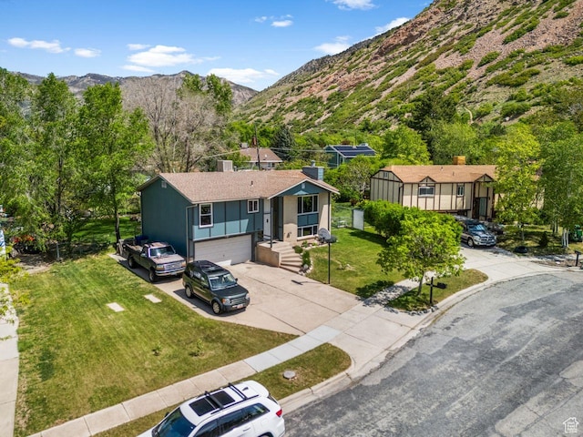 ranch-style home featuring driveway, a mountain view, a garage, a front lawn, and a chimney
