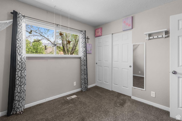 unfurnished bedroom with carpet flooring, a closet, baseboards, and a textured ceiling