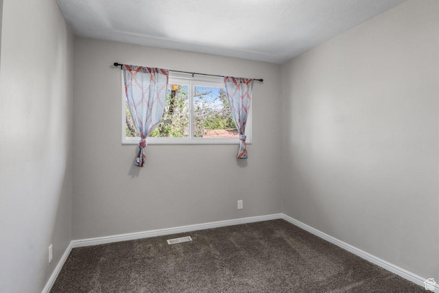 unfurnished room with dark colored carpet and baseboards