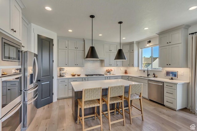 kitchen with appliances with stainless steel finishes, a sink, light wood-style floors, backsplash, and recessed lighting
