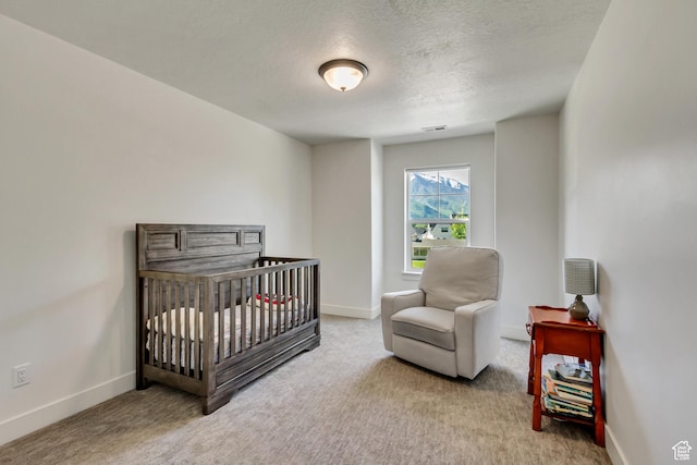 carpeted bedroom featuring baseboards, a textured ceiling, and a nursery area