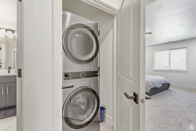 laundry room with stacked washer and clothes dryer, baseboards, carpet, and a textured ceiling