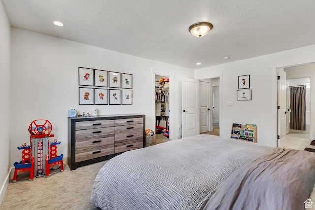 bedroom featuring carpet floors, a spacious closet, baseboards, a closet, and ensuite bathroom