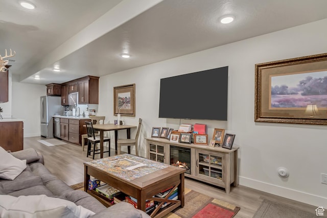 living area with light wood finished floors, baseboards, and recessed lighting