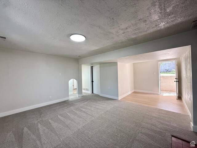 445 Havasu, Tooele, UT 84074 - empty room with light colored carpet, baseboards, a textured ceiling, and arched walkways