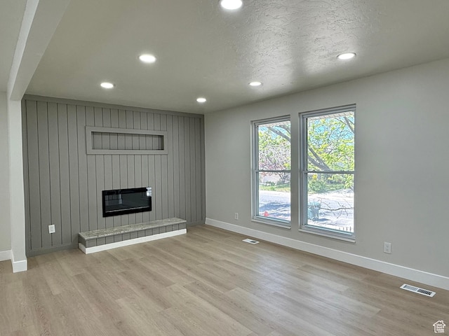 445 Havasu, Tooele, UT 84074 - unfurnished living room featuring baseboards, recessed lighting, light wood-type flooring, a tile fireplace, and a textured ceiling