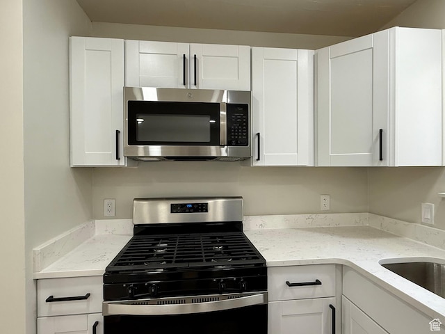 445 Havasu, Tooele, UT 84074 - kitchen featuring appliances with stainless steel finishes, white cabinets, light stone counters, and a sink
