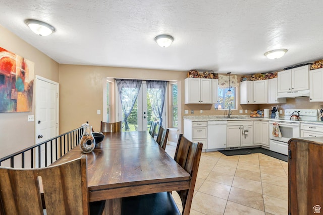 kitchen featuring white appliances, under cabinet range hood, a sink, light countertops, and white cabinets
