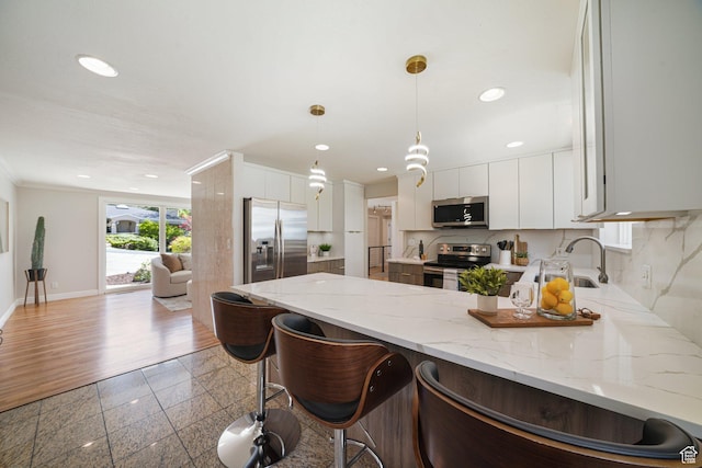 kitchen featuring stainless steel appliances, a sink, a peninsula, recessed lighting, and backsplash