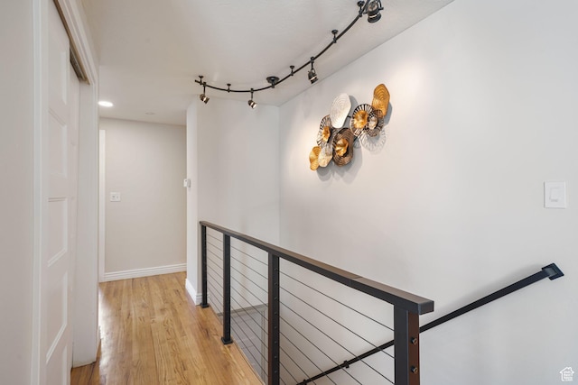 hallway with light wood-type flooring, an upstairs landing, and baseboards