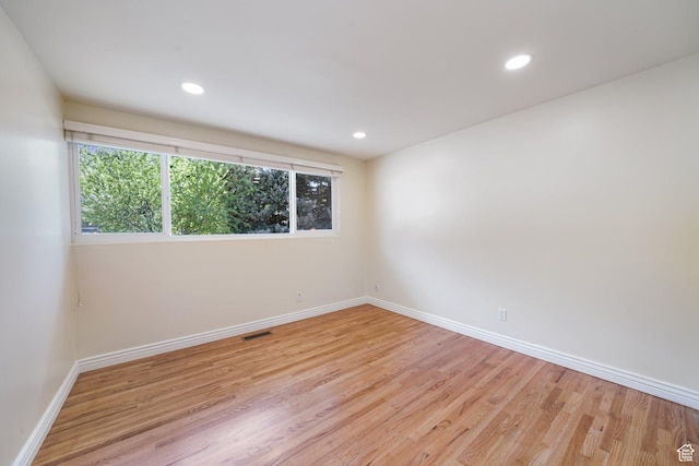 unfurnished room with healthy amount of natural light, baseboards, light wood finished floors, and recessed lighting