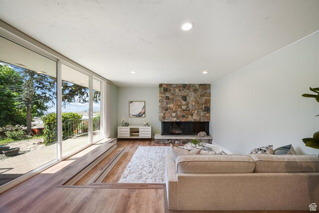3501 E Loren Von Dr, Millcreek, UT 84124 - living area with wood finished floors, a stone fireplace, a wall of windows, and recessed lighting