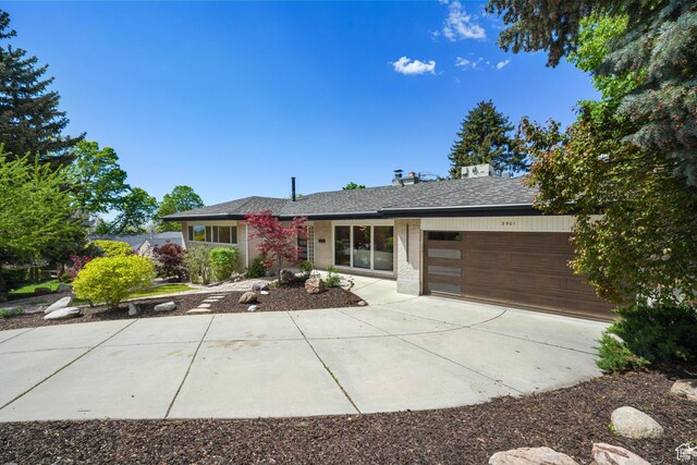 3501 E Loren Von Dr, Millcreek, UT 84124 - view of front of house with a garage, concrete driveway, roof with shingles, and brick siding