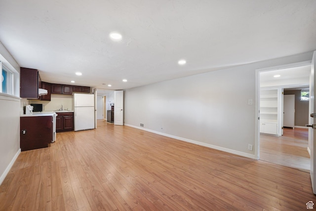 unfurnished living room with recessed lighting, a sink, baseboards, and light wood finished floors