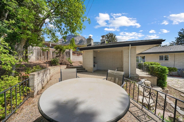 view of patio featuring outdoor dining space, fence, and a mountain view