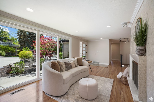 living room with ornamental molding, plenty of natural light, light wood finished floors, baseboards, and recessed lighting
