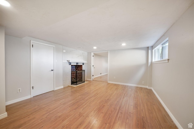 below grade area with a fireplace, light wood-type flooring, baseboards, and recessed lighting