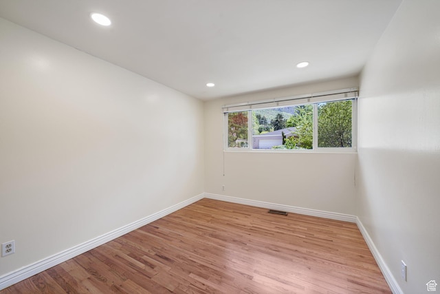 empty room featuring baseboards, light wood-style flooring, and recessed lighting