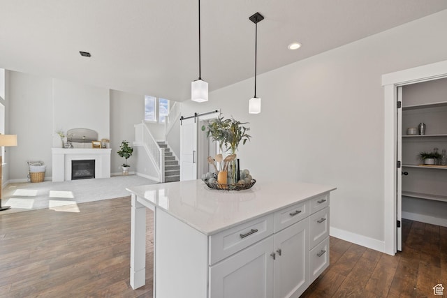 kitchen featuring a barn door, dark wood-style flooring, light countertops, pendant lighting, and a kitchen island