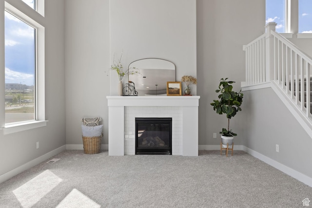 carpeted living room with healthy amount of natural light, a brick fireplace, and baseboards