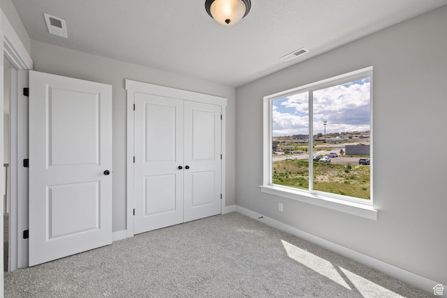 unfurnished bedroom featuring baseboards, carpet floors, and a closet