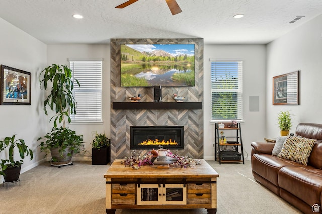 carpeted living room with ceiling fan, a textured ceiling, baseboards, a large fireplace, and recessed lighting