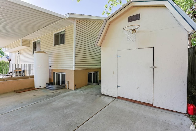 rear view of property featuring an outdoor structure, a shed, a patio, and stucco siding