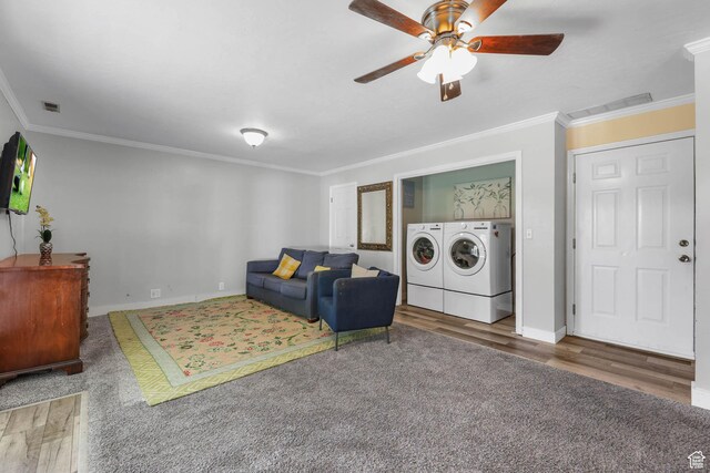 living room with washer and clothes dryer, crown molding, ceiling fan, wood finished floors, and baseboards
