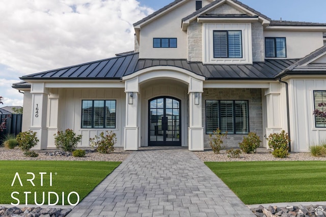 view of exterior entry featuring a standing seam roof, a yard, and board and batten siding