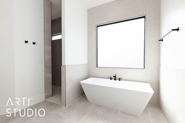 full bathroom featuring a freestanding tub, tile patterned flooring, and tile walls