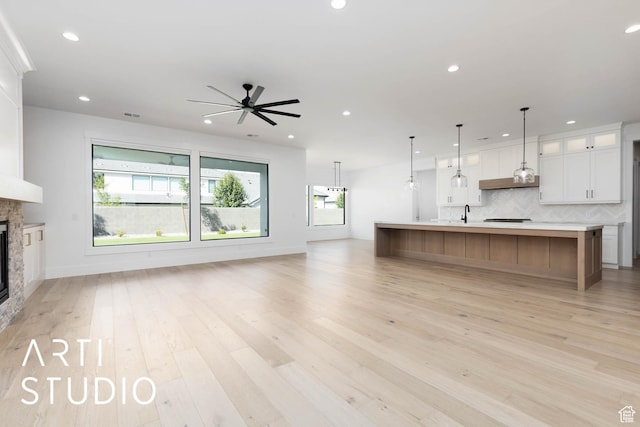 unfurnished living room featuring a ceiling fan, a fireplace, recessed lighting, light wood-style floors, and baseboards