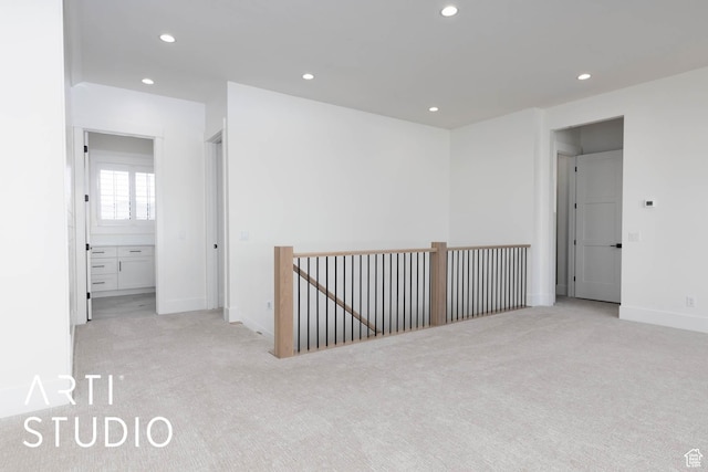 empty room featuring light carpet, recessed lighting, and baseboards