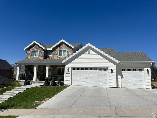 4901 N Eagle Nest Ln, Lehi, UT 84043 - view of front of home featuring a garage, driveway, covered porch, a front lawn, and stone siding