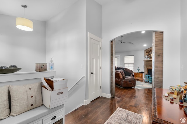 entryway featuring wood-type flooring, ceiling fan, a fireplace, arched walkways, and baseboards