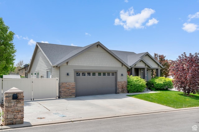 craftsman-style home with an attached garage, concrete driveway, a gate, roof with shingles, and stone siding