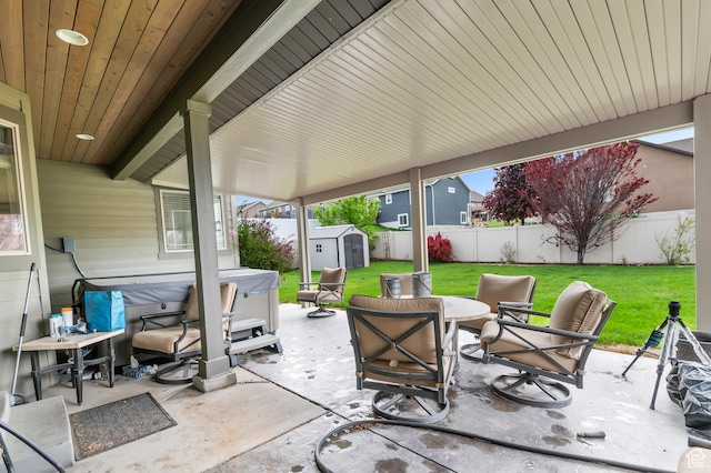 view of patio with a storage unit, a hot tub, and an outbuilding