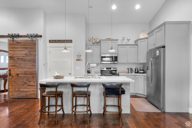 kitchen with stainless steel appliances, a sink, gray cabinetry, and a breakfast bar area