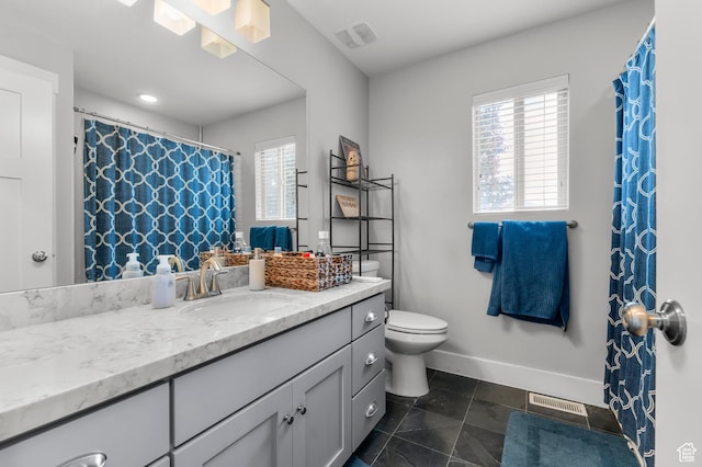 bathroom featuring healthy amount of natural light, toilet, vanity, tile patterned floors, and recessed lighting
