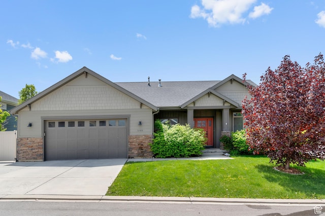 craftsman-style home featuring a garage, a front yard, concrete driveway, and stone siding