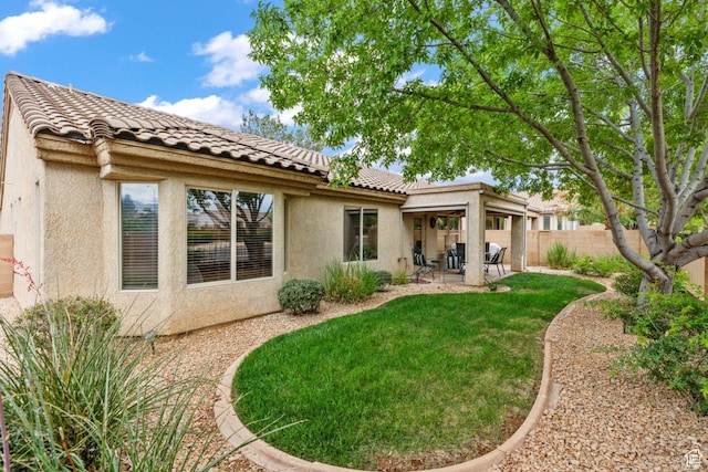 rear view of property featuring stucco siding, a patio area, and a tiled roof