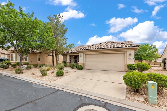 mediterranean / spanish home featuring a tile roof, concrete driveway, stucco siding, a garage, and fence