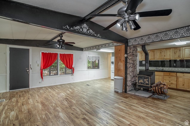 345 N Main St, Ivins, UT 84738 - unfurnished living room featuring a ceiling fan, a wood stove, light wood-style flooring, and a wainscoted wall