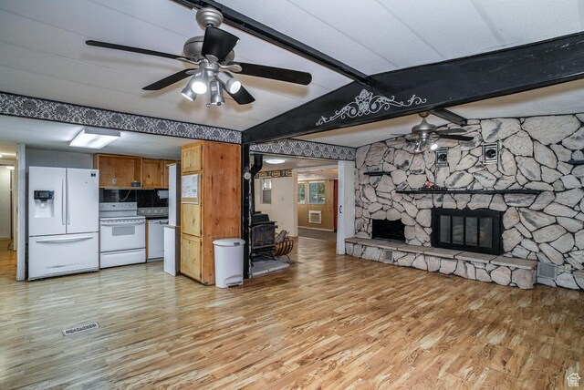 345 N Main St, Ivins, UT 84738 - unfurnished living room featuring ceiling fan, a wood stove, light wood-style flooring, and a stone fireplace