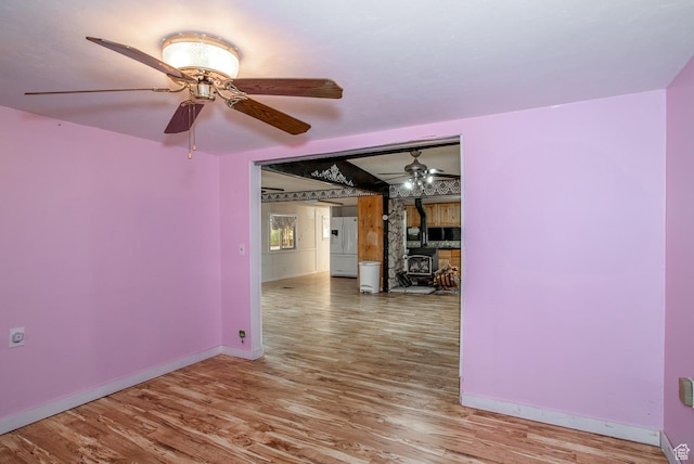 345 N Main St, Ivins, UT 84738 - unfurnished room featuring a wood stove, baseboards, wood finished floors, and ceiling fan