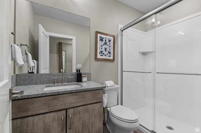 full bath featuring toilet, a stall shower, and vanity