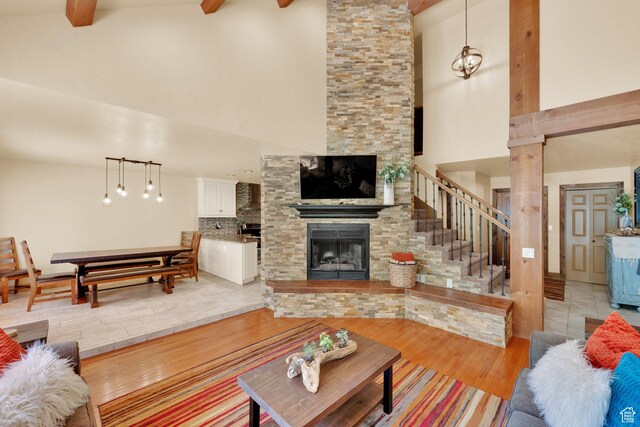 8135 S Clover Spring Ln E, Cottonwood Heights, UT 84121 - living room with high vaulted ceiling, light wood-style floors, a stone fireplace, beamed ceiling, and stairs